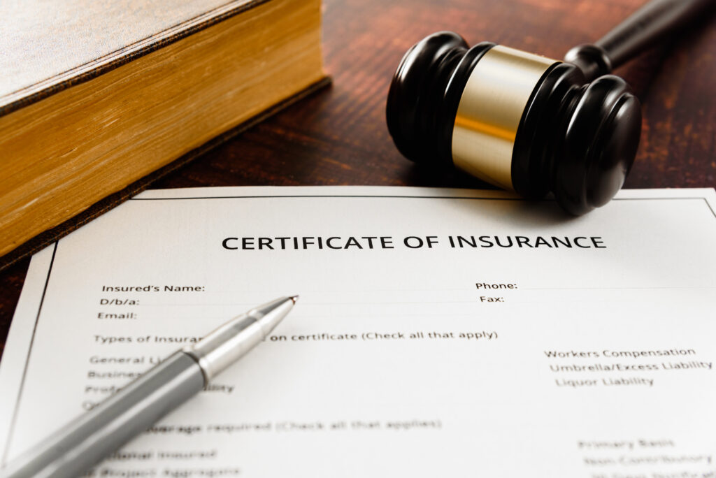 Gavel next to a certificate of insurance with a pen on top in a court focusing on insurance coverage law. 
