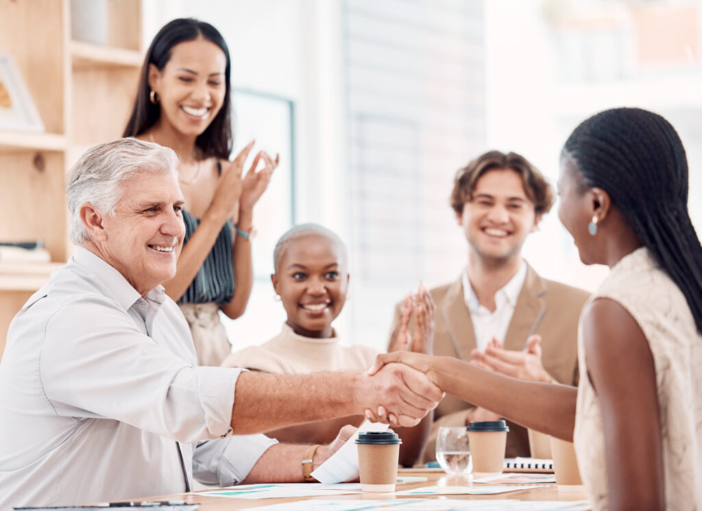 Employee shaking hands with CEO as she receives a job offer in an organization that practices pay transparency. 