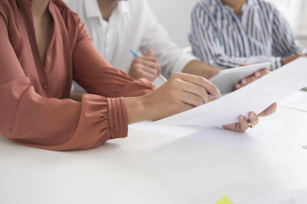 Photo focused on hands and paperwork of three individuals reviewing an estate plan to ensure it's updated due to major life events. 